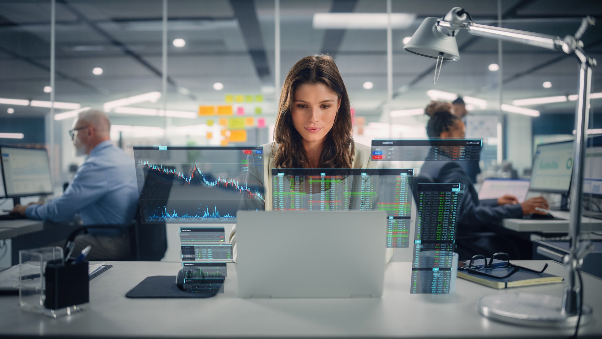 Young Happy Businesswoman Using Laptop Computer in Modern Office with Colleagues. Stylish Beautiful Financial Advisor Working. VFX Hologram Edit Visualizing Stock Exchange Interface, Opened Charts.